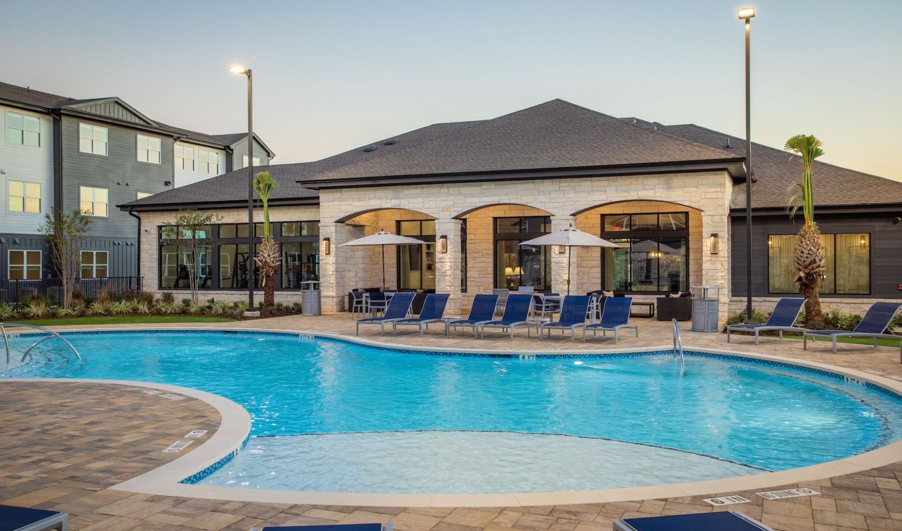 Find Your Home Today wide view of apartment community pool showing tropical landscaping in Westover Hills, San Antonio