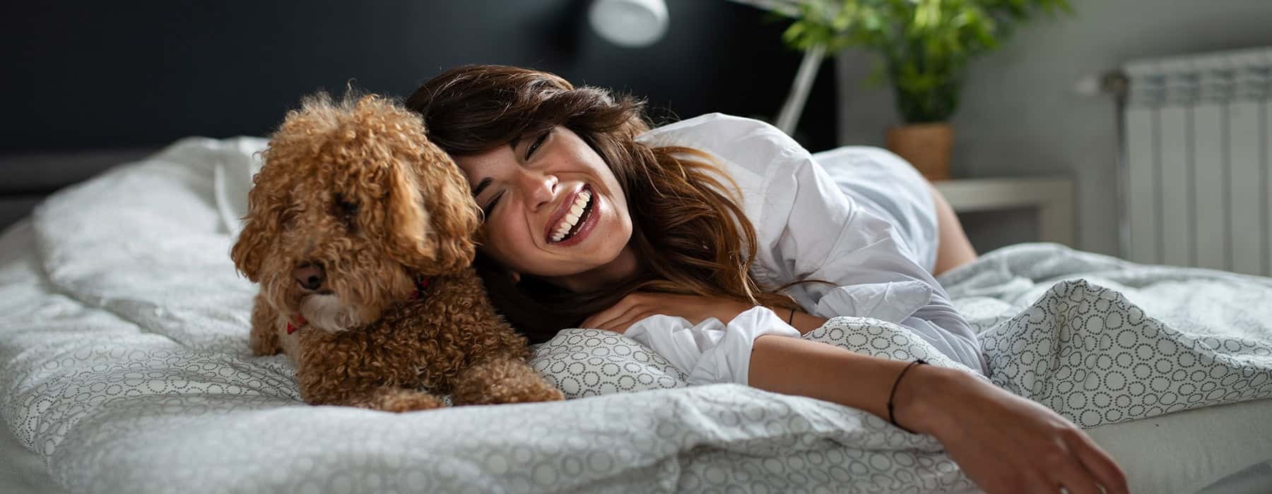 lifestyle image of a woman and a pet in a bedroom